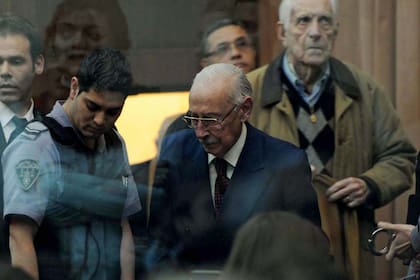 Videla ingresa a la sala de audiencias de los tribunales para escuchar la histórica sentencia, seguido de Bignone