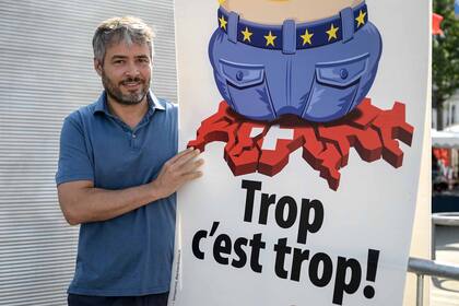 Vincent Schaller, miembro del consejo municipal de Ginebra por el derechista Partido Popular Suizo (SVP) posa el 13 de septiembre de 2020 en Ginebra con un carte anti UE que dice "Demasiado es demasiado"