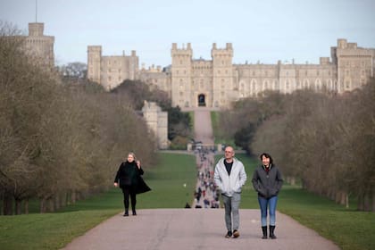 Visitantes caminan por el sendero que comunica el castillo de Windsor, al fondo, con la ciudad del mismo nombre