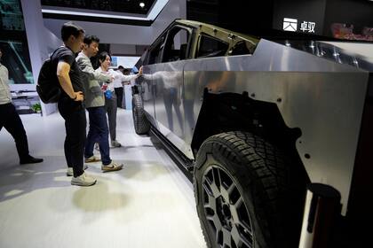 Visitantes miran una versión básica del Cybertruck de Tesla con dispositivos de AOD Technology, que fabrica unidades de control de dominio que procesan diversos comandos como abrir puertas y controlar estribos en SUV, exhibida en la feria automotriz de Shanghái el jueves 24 de abril de 2025. (AP Foto/Ng Han Guan)
