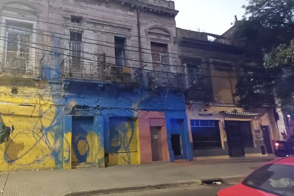 Vista completa de la fachada del inmueble clausurado en La Boca, pintada con colores vivos y grafitis, que evidencia el deterioro estructural y el tapiado en las aberturas
