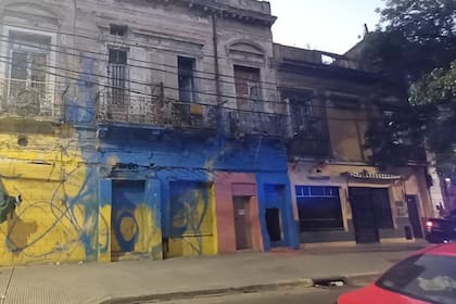 Vista completa de la fachada del inmueble clausurado en La Boca, pintada con colores vivos y grafitis, que evidencia el deterioro estructural y el tapiado en las aberturas
