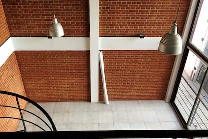 Antes: perspectiva desde el entrepiso: paredes de ladrillo a la vista, baldosas cerámicas y escalera caracol.