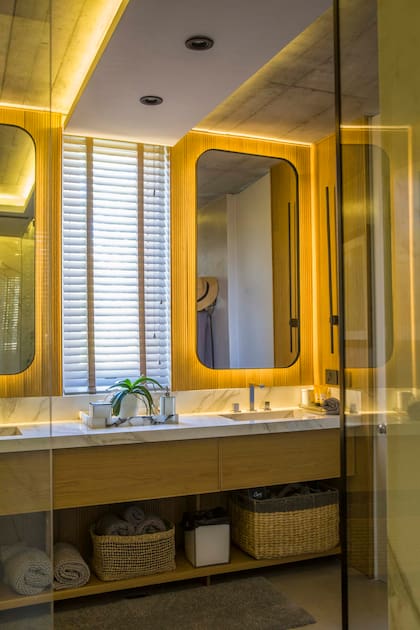 Vista desde el box de ducha con mampara al mueble con doble bacha, espejos y accesorios en negro, diseñados por Urzi y hechos a medida. En las paredes y el piso, placas de Neolith.