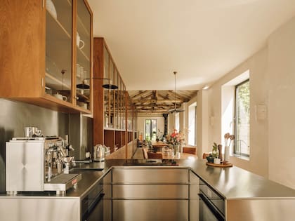Vista desde la cocina hacia el estar con chimenea junto al jardín, pasando por el comedor. Apliques de pared de cerámica artesanal (Project 213A).