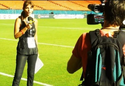 Viviana Semienchuk en una cancha de fùtbol, micròfono en mano, frente a cámara.