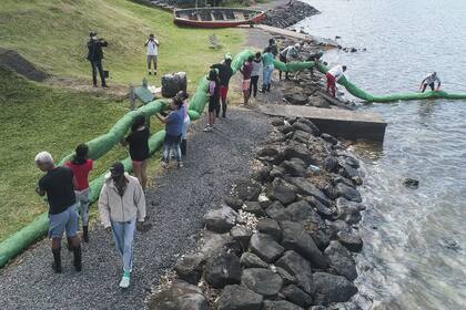 Voluntarios cargan una barrera para petróleo hecha a mano (LExpress Maurice)