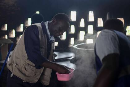 Voluntarios preparan comida para refugiados en el Asentamiento de Refugiados Rwamwanja en el distrito de Kamwenge, Uganda el 21 de octubre de 2024. (AP Foto/ Patrick Onen)