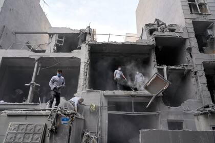Voluntarios retiran escombros de un edificio residencial dañado cuando una comisaría cercana fue atacada el viernes en un ataque de Israel y Estados Unidos en Teherán, Irán, el domingo 15 de marzo de 2026. (AP Foto/Vahid Salemi)