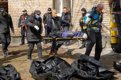 Voluntarios reúnen cuerpos de civiles asesinados en Bucha, cerca de Kiev, Ucrania, el lunes 4 de abril de 2022.  (AP Foto/Efrem Lukatsky)