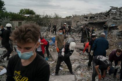 Voluntarios trabajan para despejar escombros en un lugar donde varias casas quedaron destruidas tras un ataque ruso en una zona residencial de Zaporiyia, Ucrania, el domingo 9 de octubre de 2022. (AP Foto/Leo Correa)