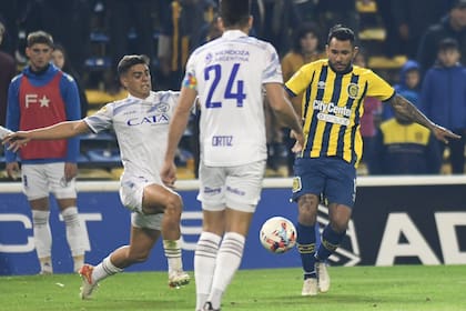 Walter Montoya, de Rosario Central, es perseguido por Juan Meli, carrilero de Godoy Cruz; Ortiz lo espera de frente