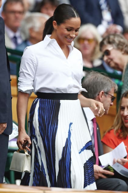 Tras haber sido criticada días antes por usar jeans en esta cita deportiva, esta vez, Meghan optó por combinar una camisa de Givenchy con una falda plisada, que marcaba su cuerpo posparto.