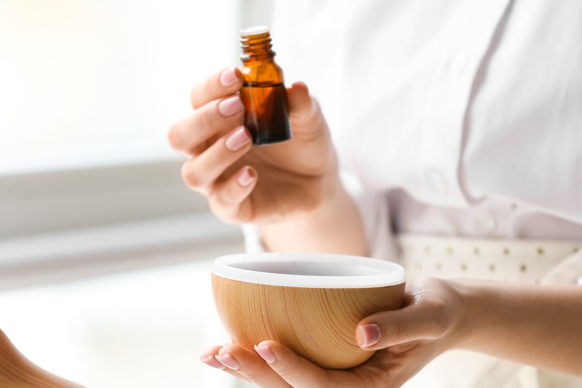Woman adding essential oil to aroma diffuser