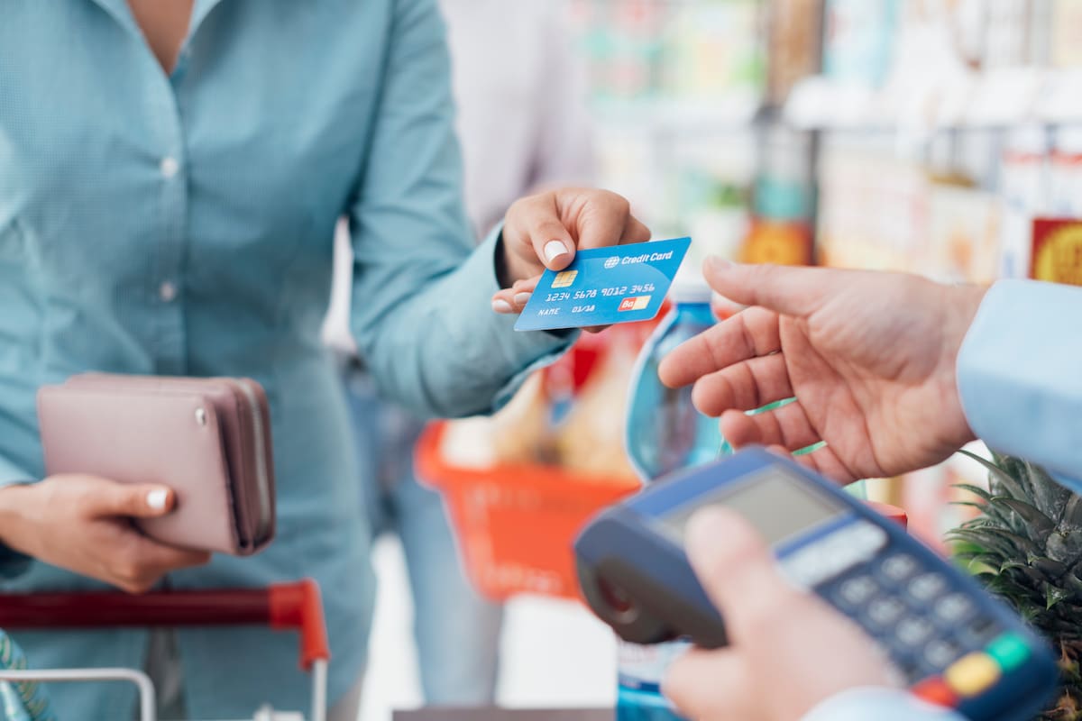 Woman at the supermarket checkout, she is paying using a credit card, shopping and retail concept