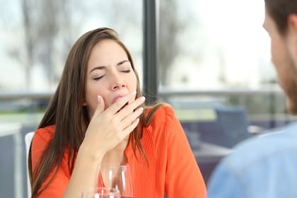 Woman bored or tired yawing in a bad date in a coffee shop with a window in the background