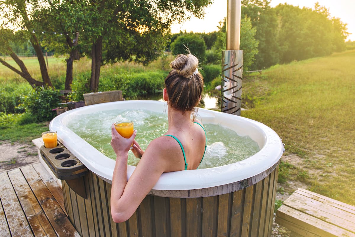 Woman enjoy outside ofuro japanese hot tub in romantic nature environment. Idyllic bathtub in sunset