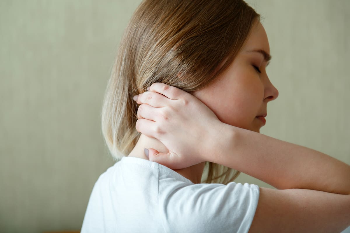 Woman holds neck with pain cervical muscle spasm by hand. Neck pain, cervical vertebrae, Disease of musculoskeletal system in young woman
