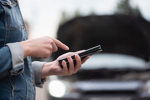 Woman with mobile phone on the broken car background. Tow truck service. Car service call.