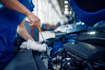 Worker checks the engine oil level, car service