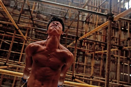 Worker Shi Shenwei performs a high bar routine on a scaffolding at the construction site of a Buddhist temple in the village of Huangshan, near Quanzhou, Fujian Province, China