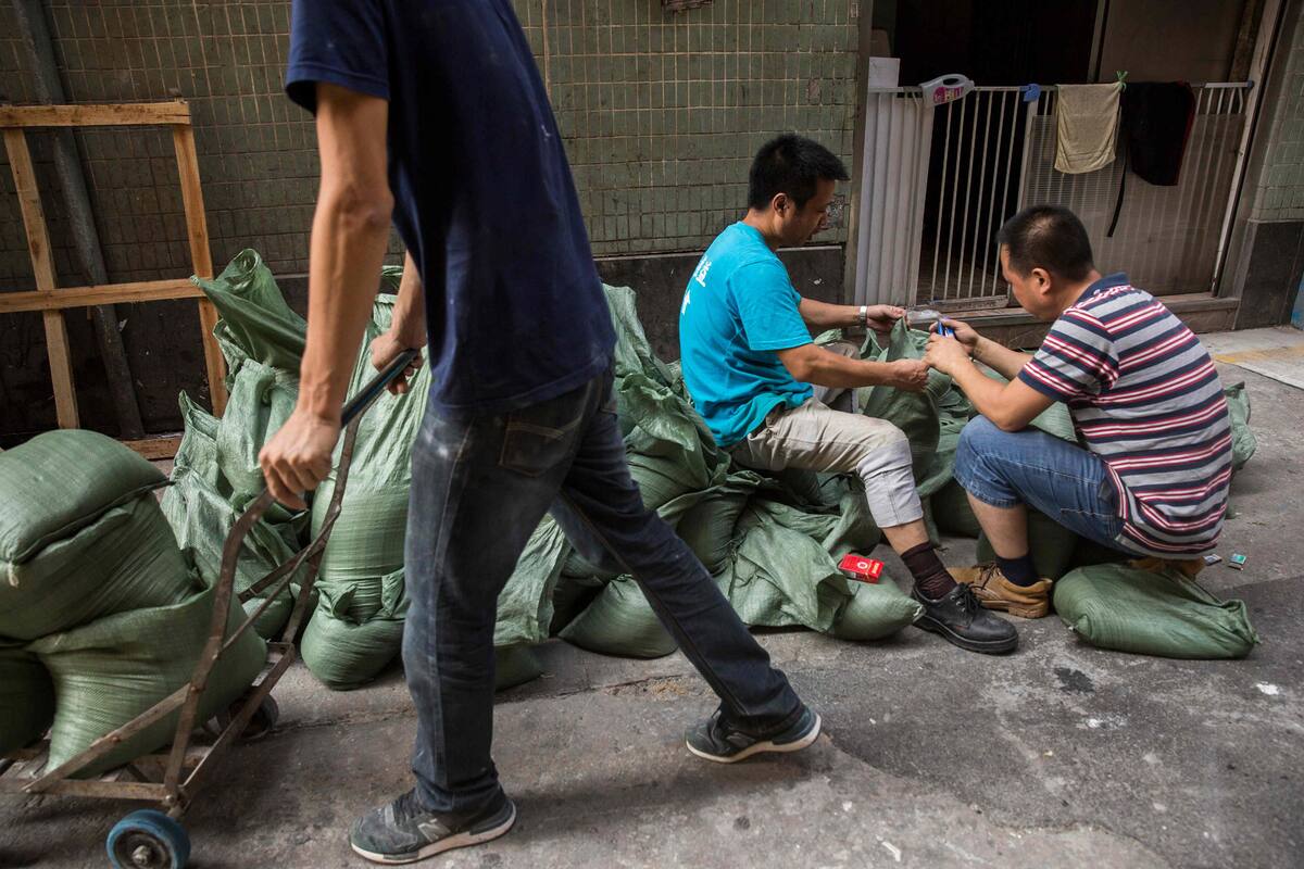 Workers (R) seal sand bags that will be used to stop flooding before the expected arrival of Super Typhoon Mangkhut in Macau on September 15, 2018. (Photo by ISAAC LAWRENCE / AFP)