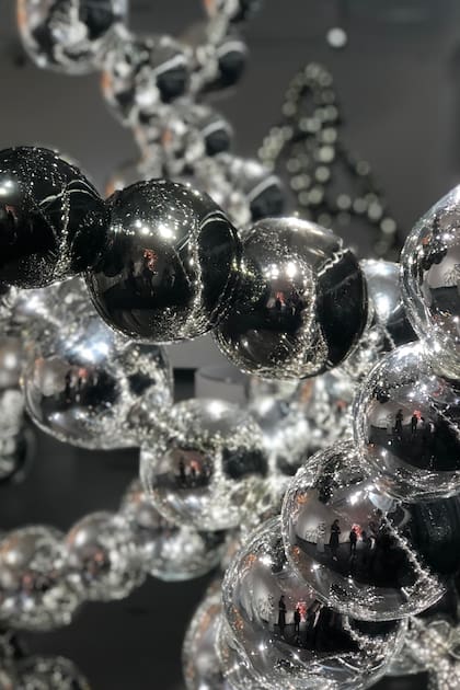 Todos esos collares, a su vez, se reflejan en el espejo que funciona como base de la obra y en los vidrios que separan la sala del pasillo, en un loop psicodélico que parece no tener final