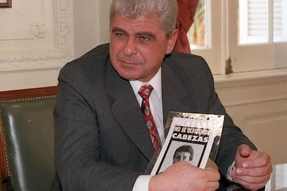 Yabrán, en 1997, meses después del crimen, exhibe una foto del símbolo de reclamo de Justicia en una reunión en la Casa de Gobierno