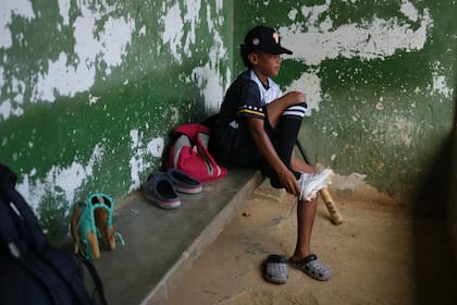 Yeferson Seijas se pone sus zapatos deportivos para un entrenamiento de béisbol en La Guaira