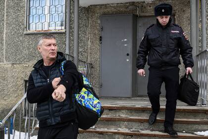Yevgeny Roizman, exalcalde y crítico del Kremlin, camina escoltado por un oficial de policía en Ekaterimburgo, Rusia, el jueves 16 de marzo de 2023. (Foto AP/Vladimir Podoksyonov)