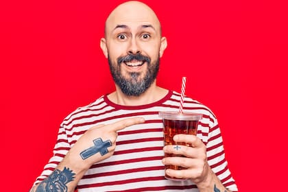 Young handsome man drinking glass of cola beverage smiling happy pointing with hand and finger