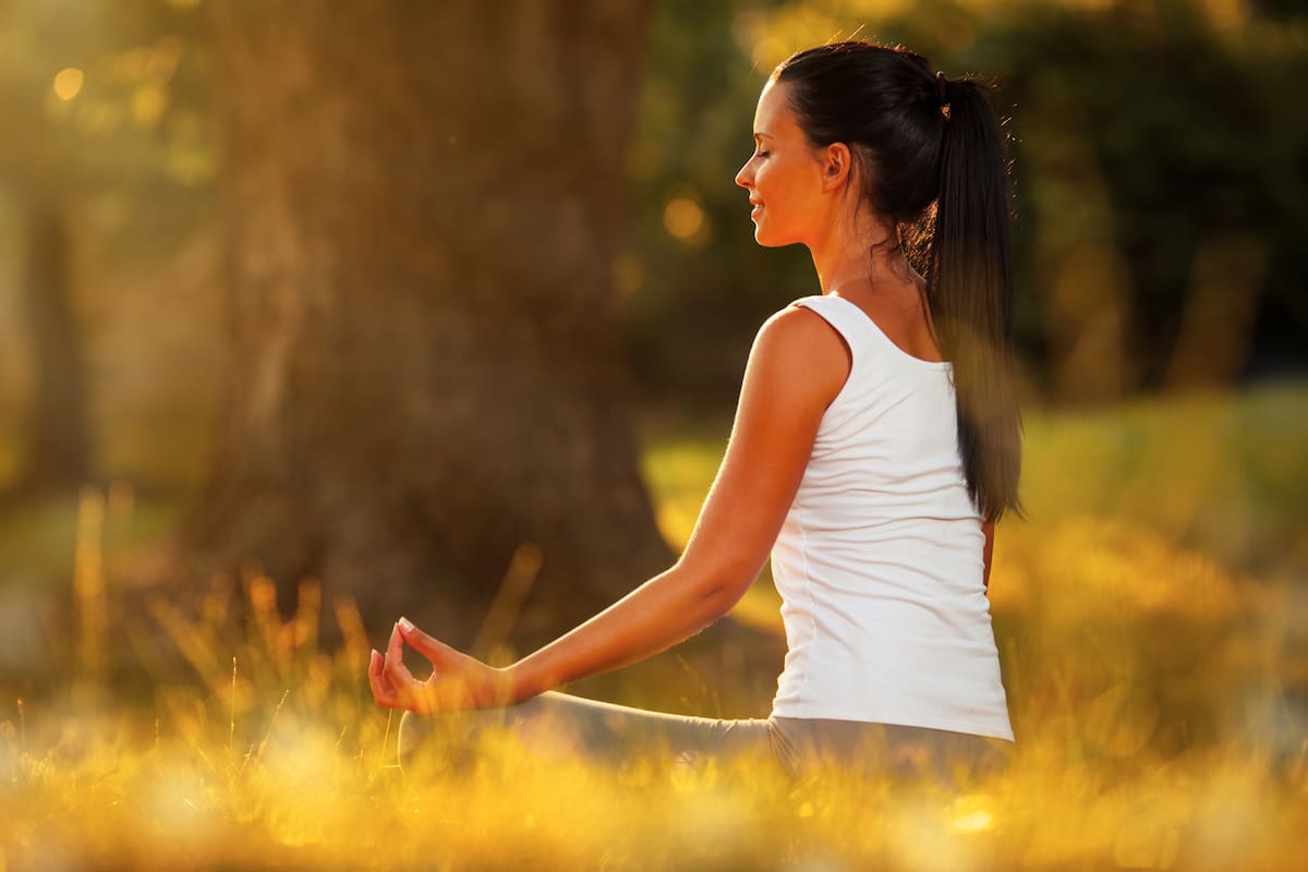 Young woman practicing morning meditation in nature at the park. Health lifestyle concept.