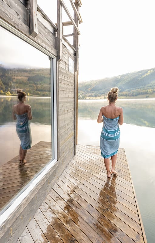 Young woman relaxing outside a in floating sauna, she contemplates nature