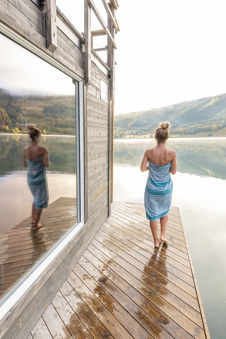 Young woman relaxing outside a in floating sauna, she contemplates nature