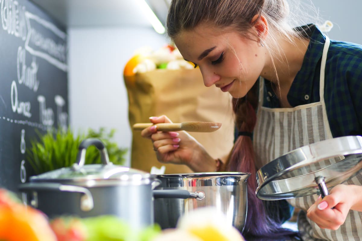 Young woman standing by the stove in the kitchen .