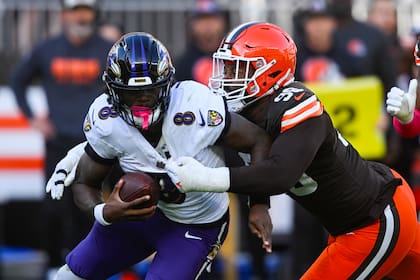 Za'Darius Smith (99), de los Browns de Cleveland, captura detrás de la línea al quarterback Lamar Jackson (8), de los Ravens de Baltimore, durante la segunda mitad del juego de la NFL del domingo 27 de octubre de 2024, en Cleveland. (AP Foto/David Richard)