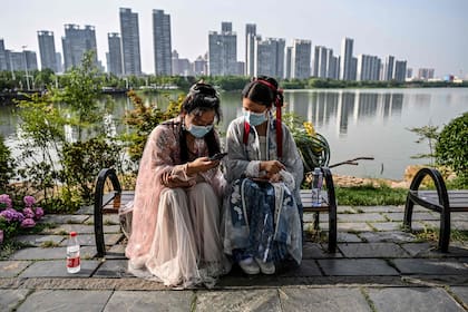 Zona cero pandémica. Dos mujeres conversan junto a un lago al este de Wuhan
