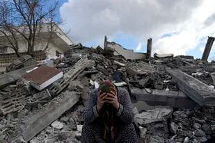 Una mujer sentada sobre los escombros de un edificio que se derrumbó por el sismo del lunes en Nurdagi, sur de Turquía, el martes 7 de febrero de 2023. (AP Foto/Khalil Hamra)
