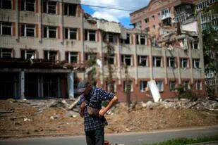 Un residente de pie junto a un edificio muy dañado en un bombardeo ruso enfrente de su casa en Bakhmut, en el este de Ucrania, el martes 24 de mayo de 2022. (AP Foto/Francisco Seco)