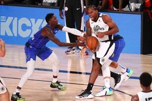 El alero de los Dallas Mavericks, Dorian Finney-Smith, izquierda, y el guardia Luka Doncic roban el balón al alero de Los Angeles Clippers Kawhi Leonard durante la segunda mitad del Juego 5 de una serie de playoffs de primera ronda de baloncesto de la NBA, el martes 25 de agosto de 2020 en Lake Buen