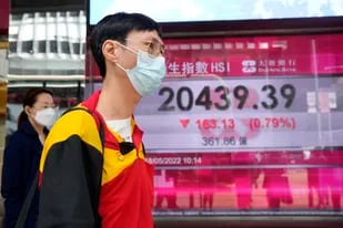 Una persona frente a una cartelera financiera en Hong Kong el 18 de mayo del 2022.  (Foto AP/Kin Cheung)