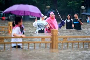 Personas caminan en calles inundadas en Zhengzhou, provincia de Henan, China, el martes 20 de julio de 2021. (Chinatopix vía AP)