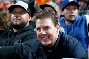 El actor Tom Cruise sonríe durante un juego de béisbol que disfrutó junto a su hijo Connor, que aparece a su lado con un buzo negro y una gorra